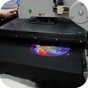 Prensa de calor aplicando un gráfico de remolino vibrante en una camiseta negra, proceso de transfer UV DTF para impresión duradera de ropa personalizada.